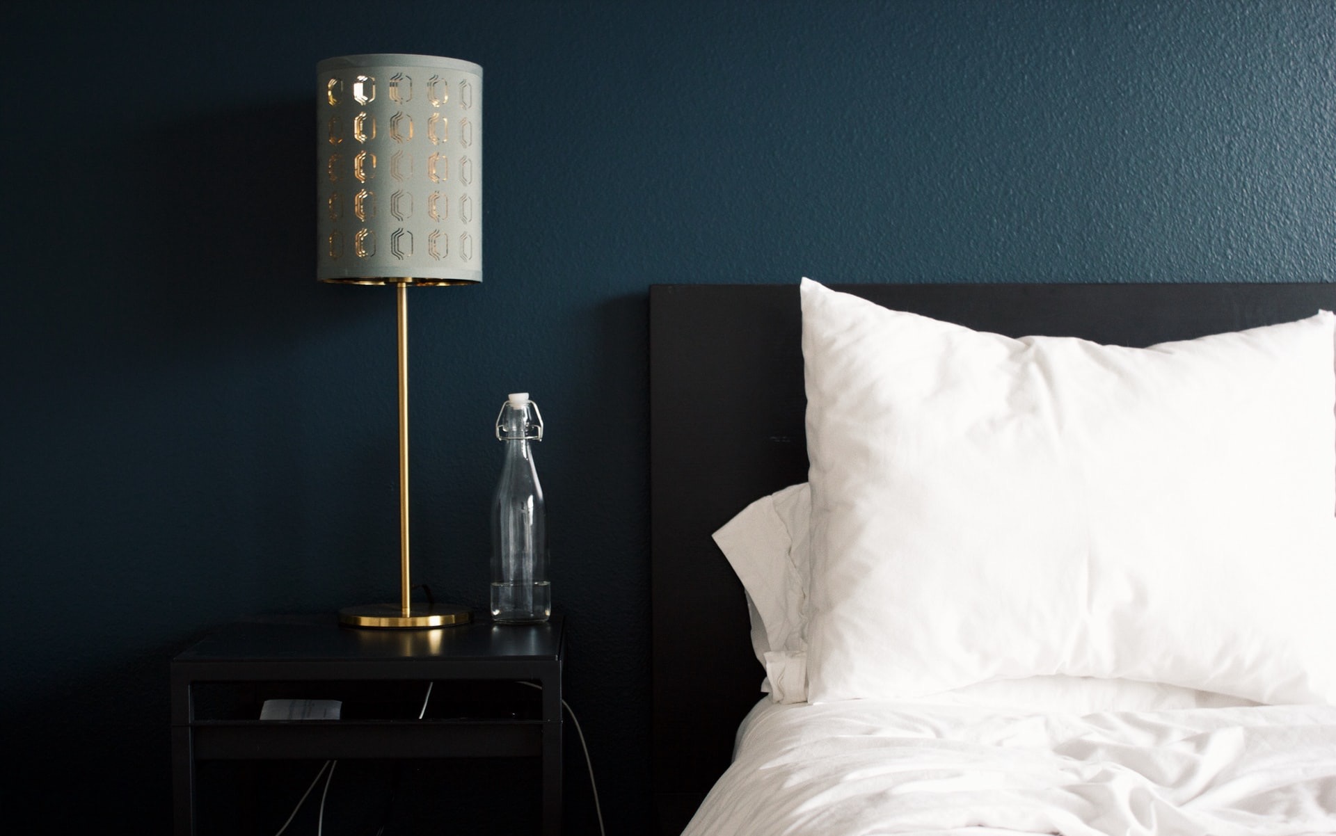 gray table lamp beside white bed pillow