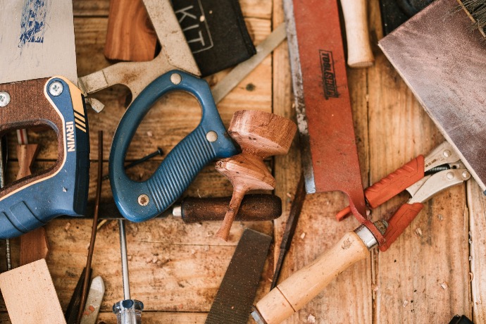 blue and black handle pliers beside brown wooden handle